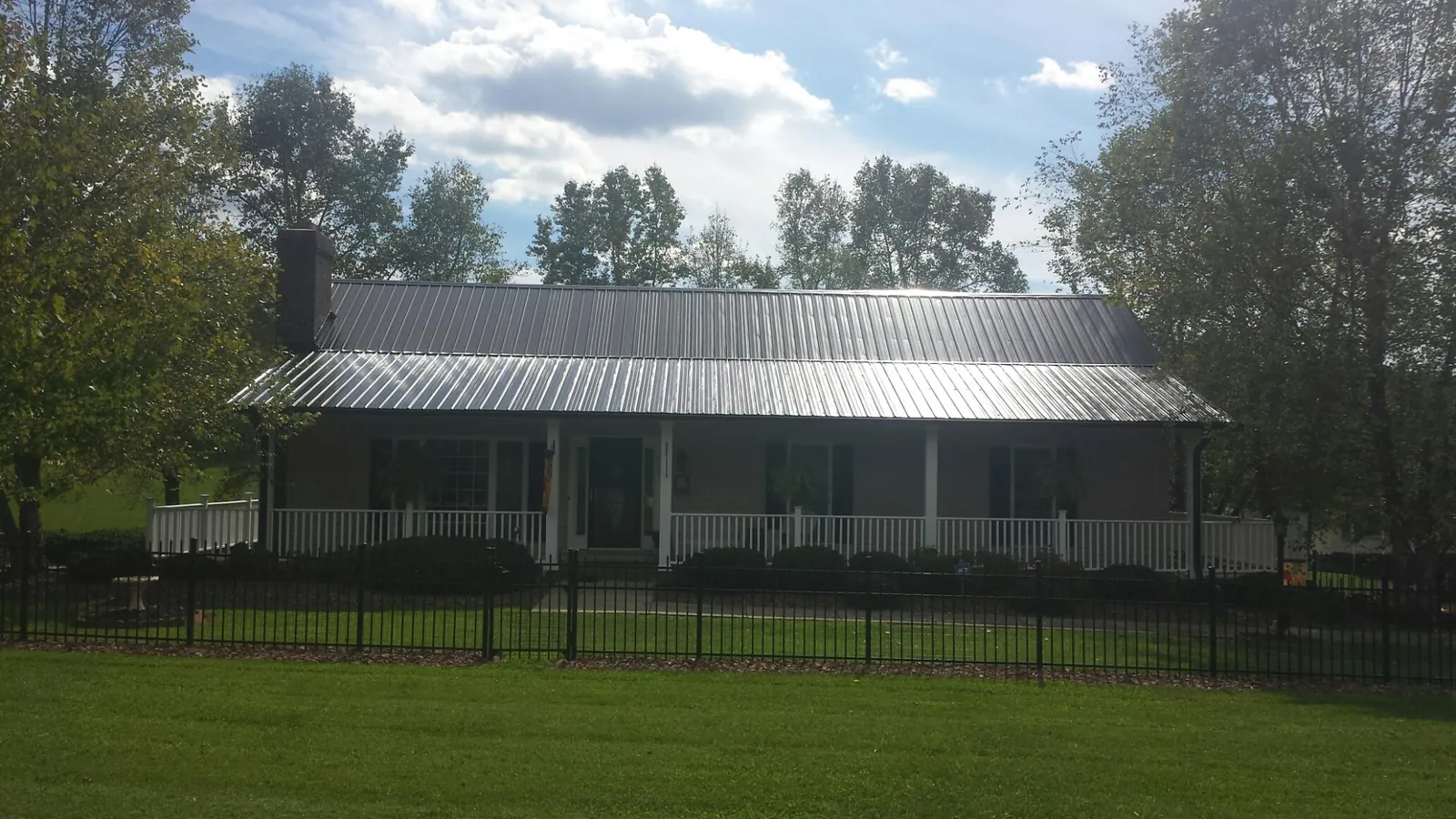 Gray metal roof on a brick ranch with a full width front porch — Gutter Guard Installation work by our crew in Cimarron