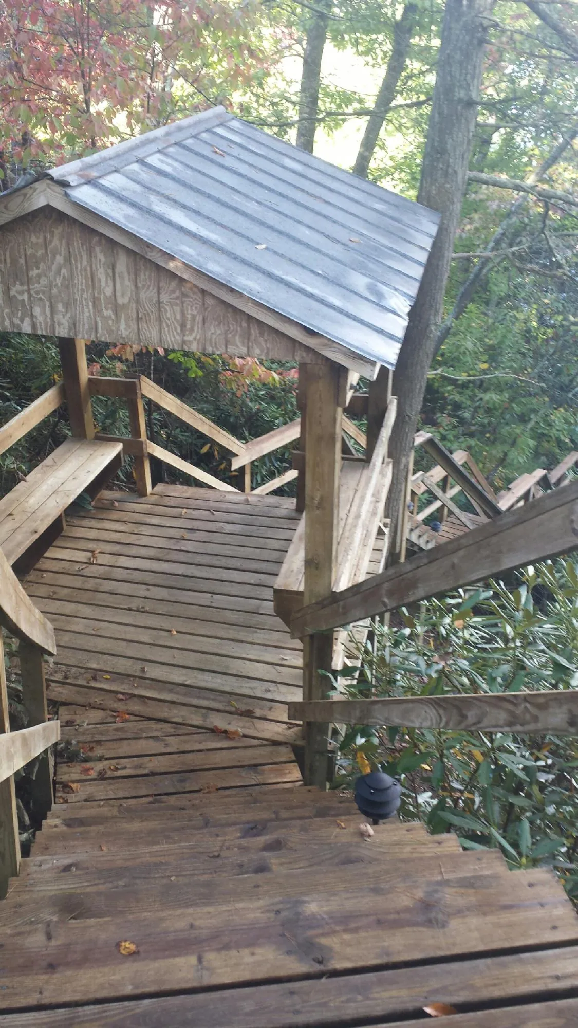 Metal roofed shelter over wooden steps on a wooded walkway — Skylight Repair & Installation work by our crew in Cimarron