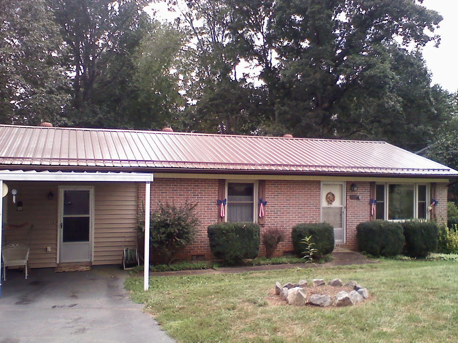 Bronze metal roof and carport on a brick ranch home — Roof Repair work by our crew in Cimarron