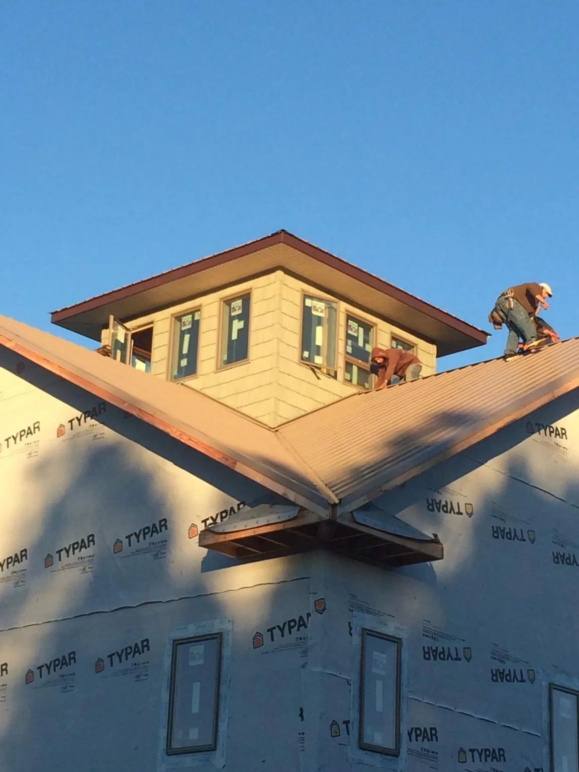 Roofers working around a rooftop cupola on a new metal roof at sunset — Roof Waterproofing in Cimarron by Roofing Brothers